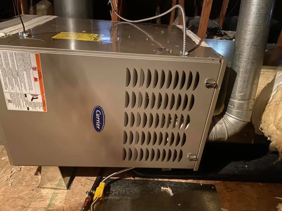 Carrier gas furnace with metal cabinet, ventilation louvers, and connected ductwork