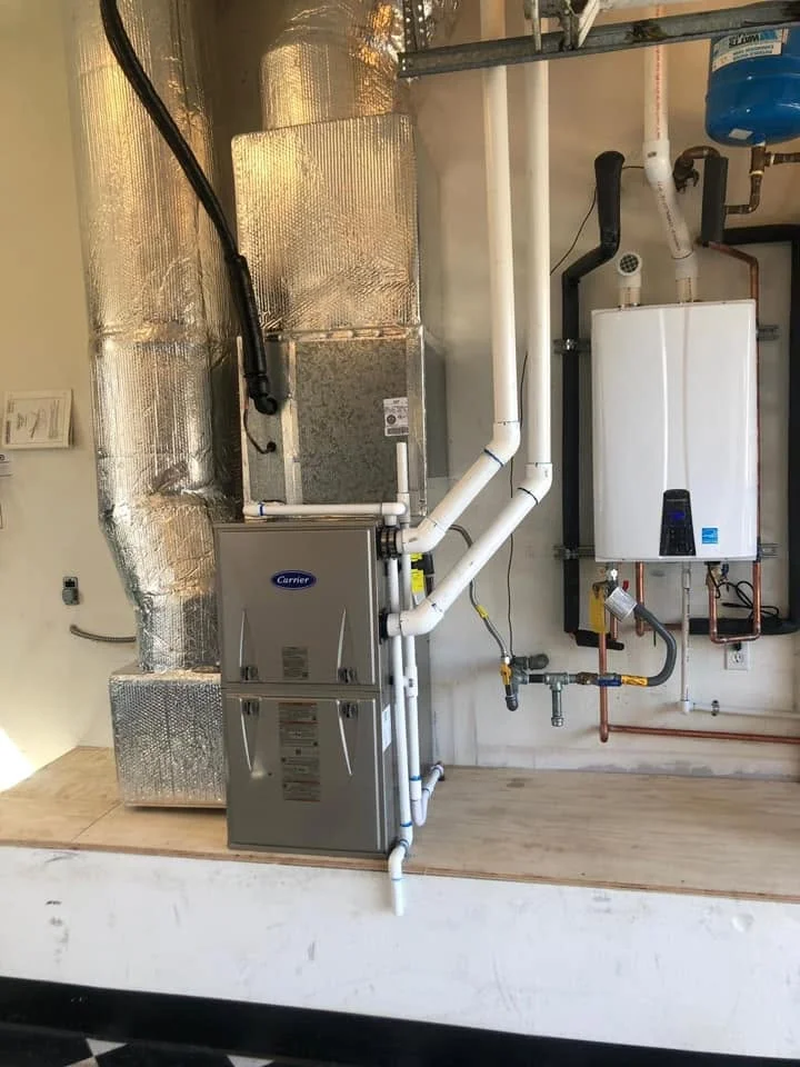Carrier furnace with white PVC ductwork, insulated supply duct, and tankless water heater installation