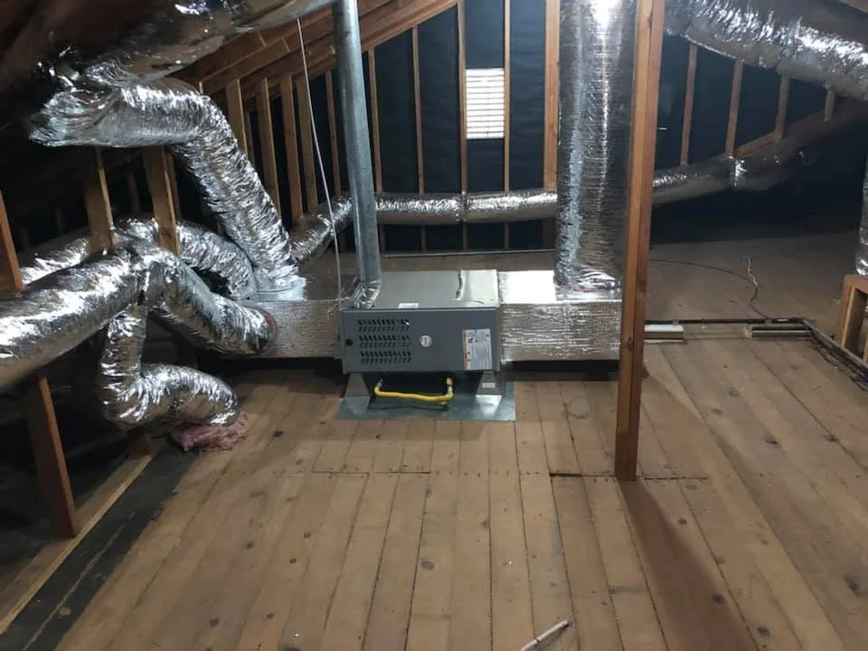 HVAC air handler and insulated ductwork installation in attic with wood framing