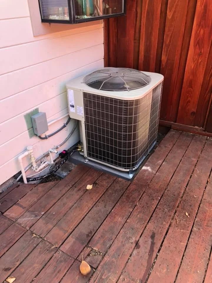 New AC condenser unit installed on deck with refrigerant lines and electrical connections