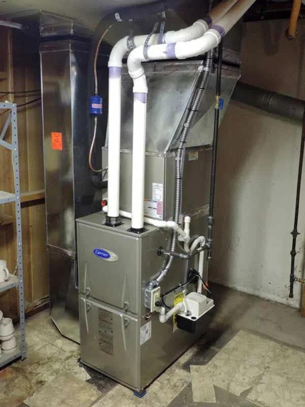 Carrier furnace with white PVC ducts and flexible connectors installed in basement