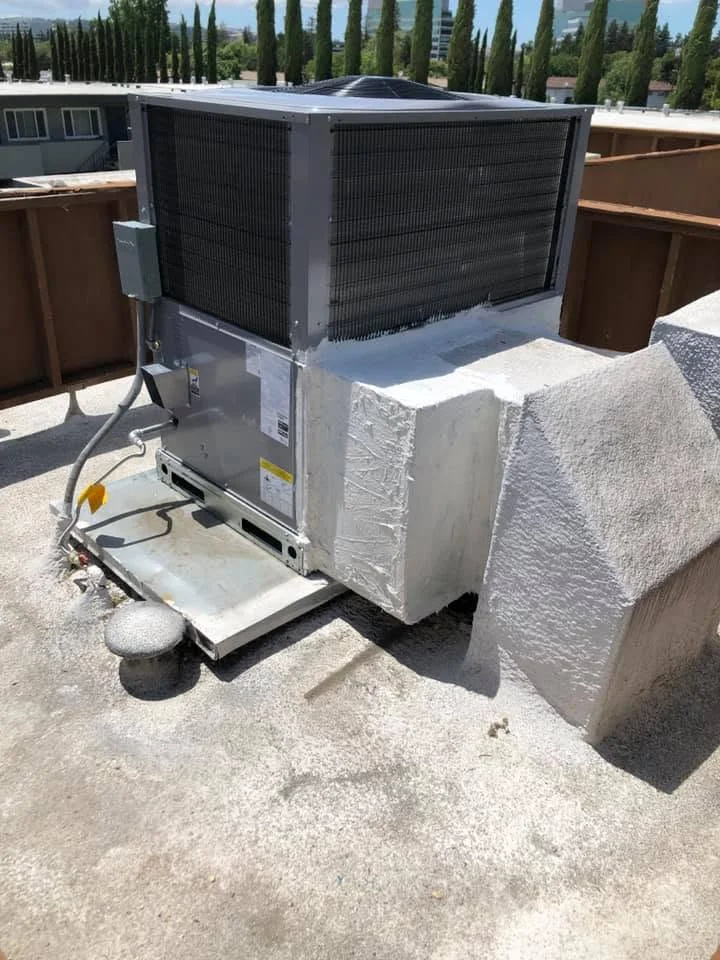 Commercial HVAC condenser unit installed on concrete pad with vibration isolators and electrical connections
