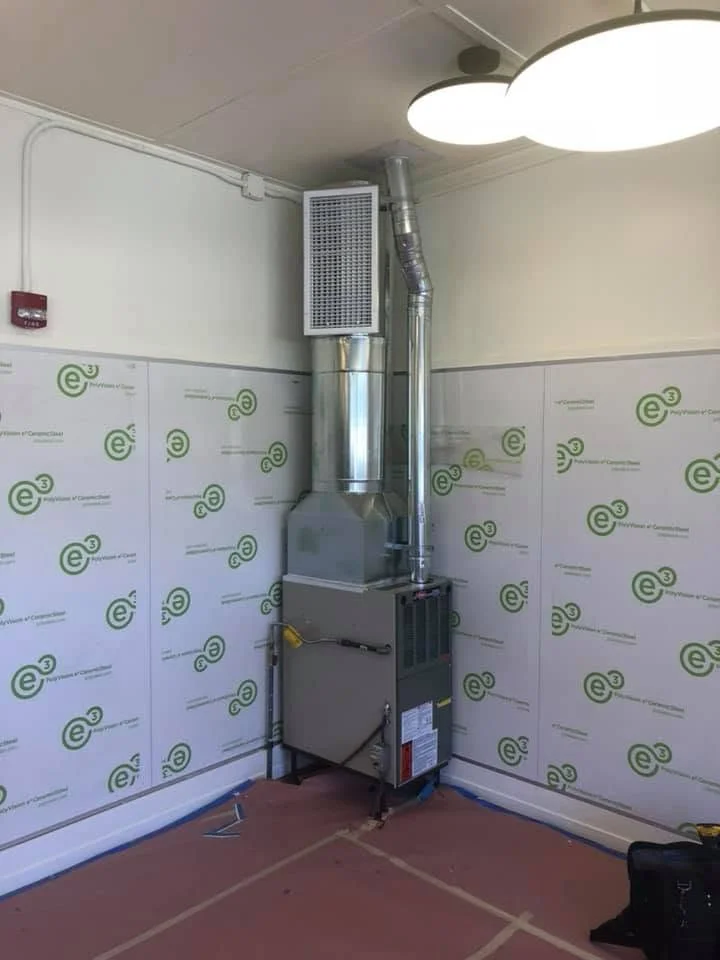 Installed commercial HVAC unit with metal ductwork, air handler, and piping in finished interior space